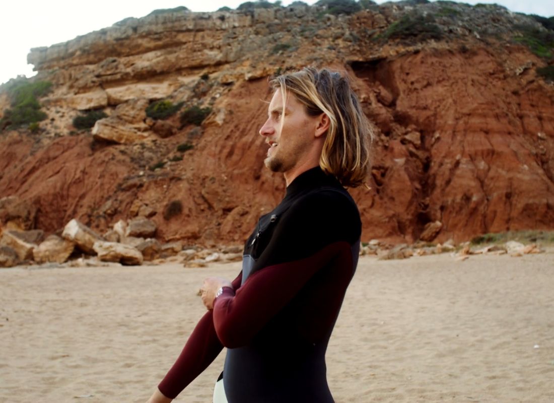 momak u neoprenskom odelu stoji na plaži